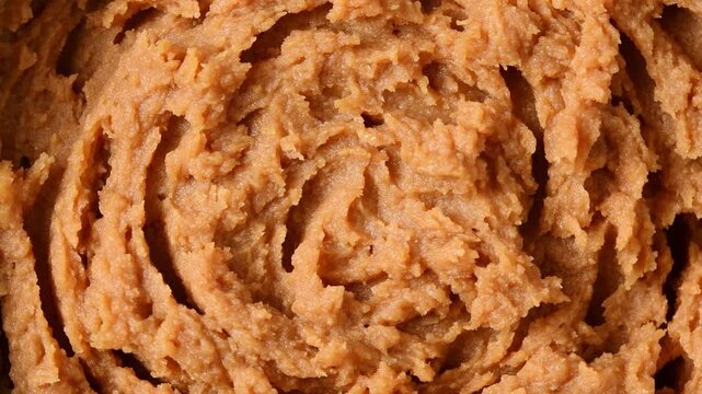 A rotating macro view reveals the dense, grainy texture of shiro miso paste in circular swirls.