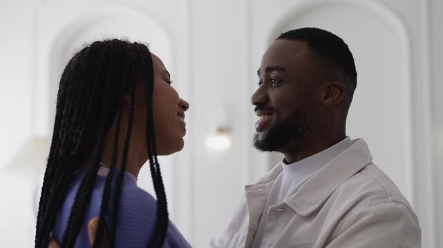 Cheerful young African American woman hugs and talks with her loving boyfriend