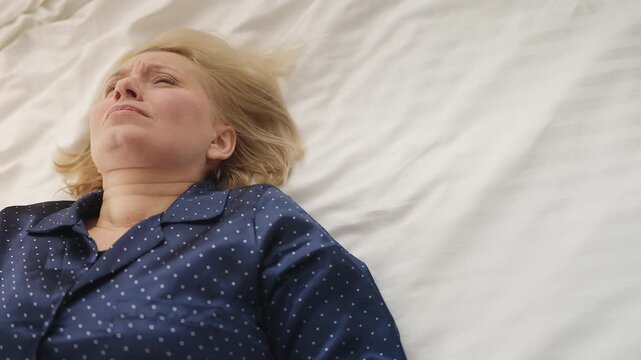Tired middle-aged woman falls onto bed in morning after not getting enough sleep