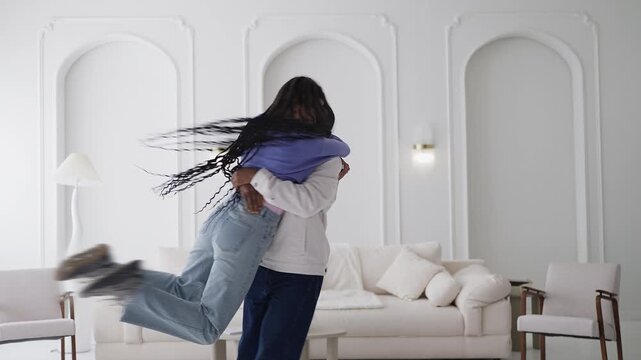 Happy African American man lifts and spins his girlfriend, love and joy at home