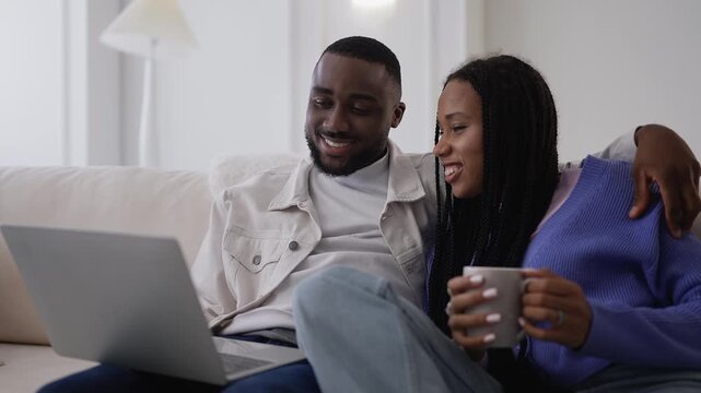 Young Black couple choosing hotel for vacation while shopping online on laptop