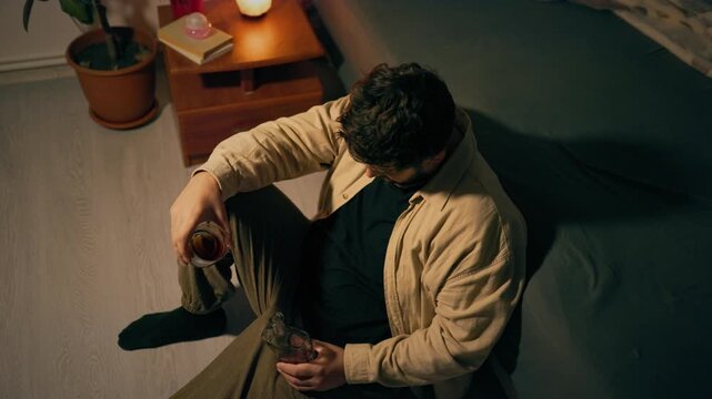 Coping with trauma through alcohol as solitary adult male holds glass. Profound loneliness sorrow