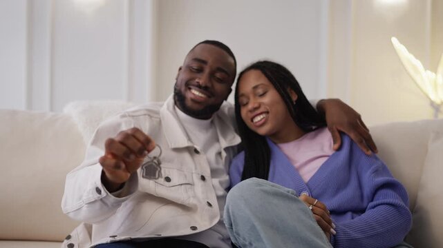 Young Black married couple hold apartment key, happy about home purchase