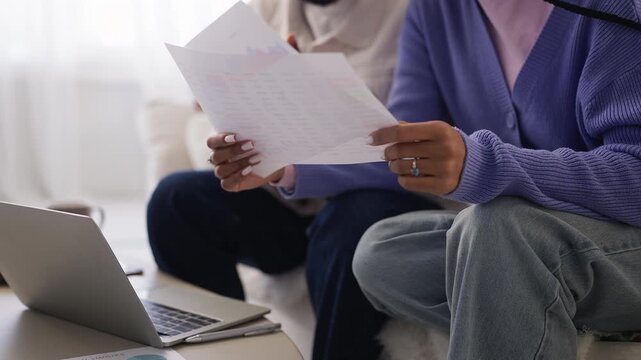African American couple review paperwork and online data for investments
