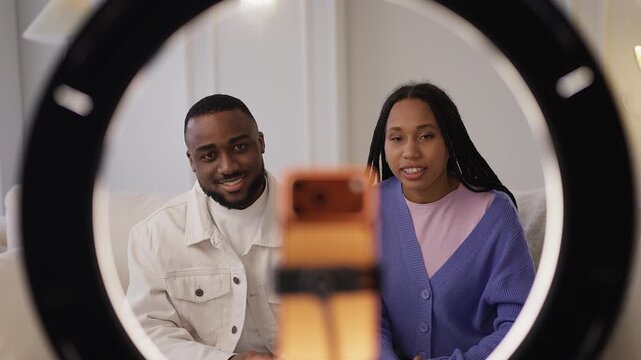 Smiling Black couple record social media vlog video on smartphone together