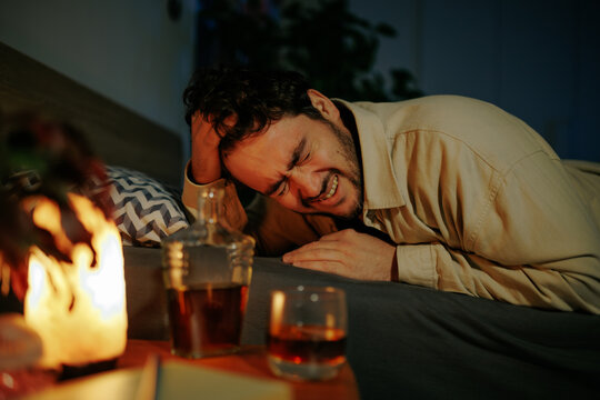 Adult male lies motionless in deep sleep across bed sheets. Overwhelming personal life crisis