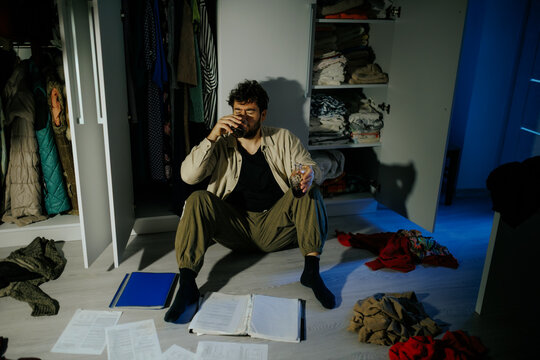 Troubled man reads painful legal decisions holding alcohol glass. Family crisis and grief pain