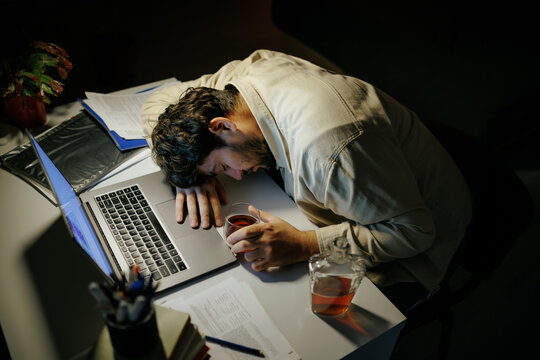 Depressed professional copes with business loss drinking alcohol at night. Burnout trauma pain