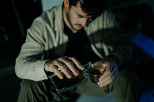 Desperate adult consumes alcohol alone on bedroom floor to escape pain. Severe depression grief
