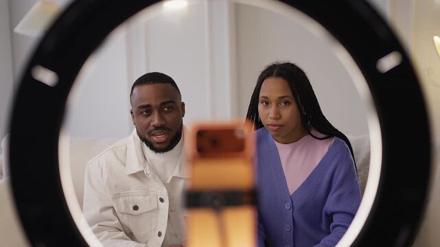 Young African American couple recording social media content on phone at home