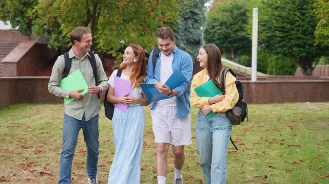 Happy university students walking together on campus lawn