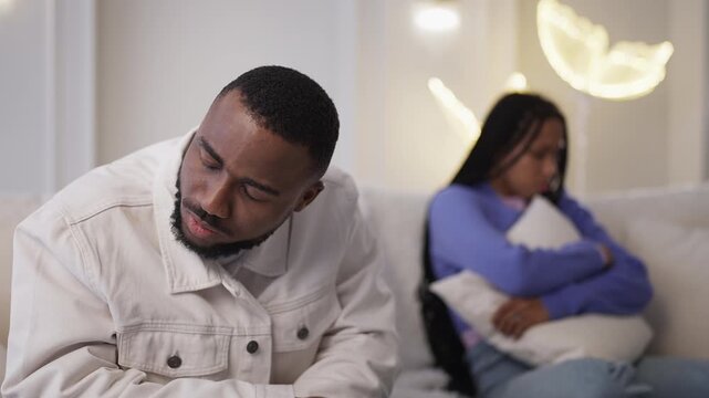 Black man feels upset after fight with girlfriend, sitting apart on couch