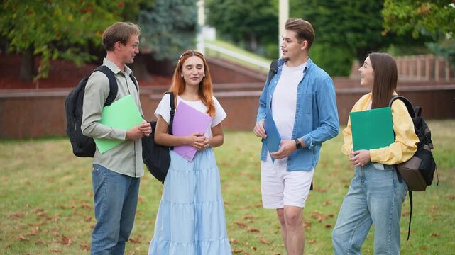 Group of university students talking on campus lawn