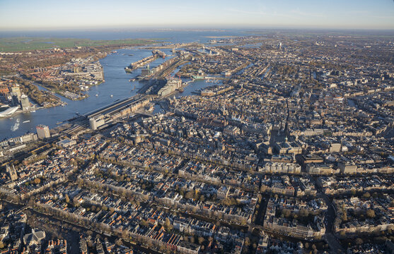 Aerial view of the historic city of Amsterdam, featuring its iconic canal network, dense urban architecture, and the IJ river waterfront in Amsterdam, North Holland, Netherlands.