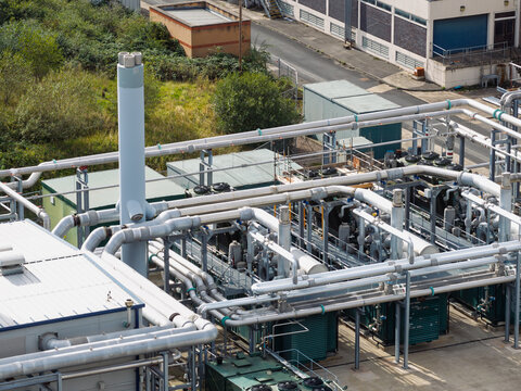 Aerial view of a water treatment facility featuring complex industrial piping, cooling units, and a tall exhaust stack, United Kingdom.