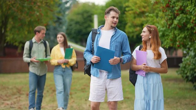 University students walking and talking together on campus lawn