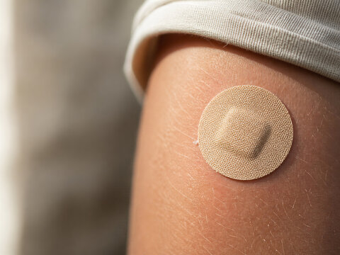 Round fabric plaster on upper arm after seasonal vaccination visit
