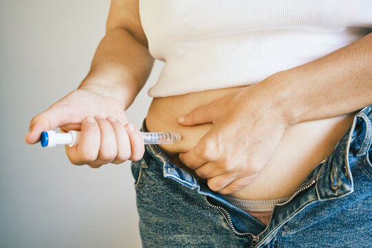 Woman self-injecting medication into her stomach, managing health with daily treatment