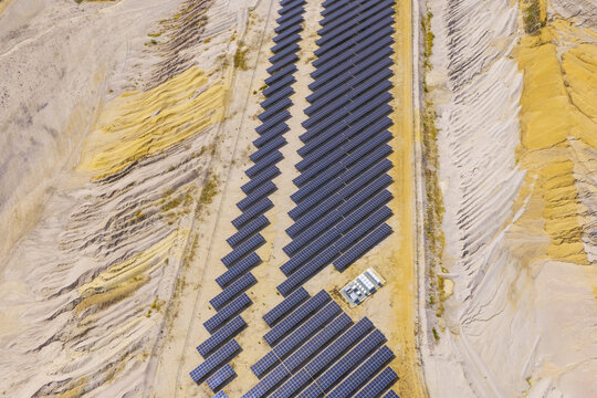 Aerial view of solar panels installed in the Hambach open-pit coal mine, showing rows of photovoltaic modules on sandy terrain in Germany.