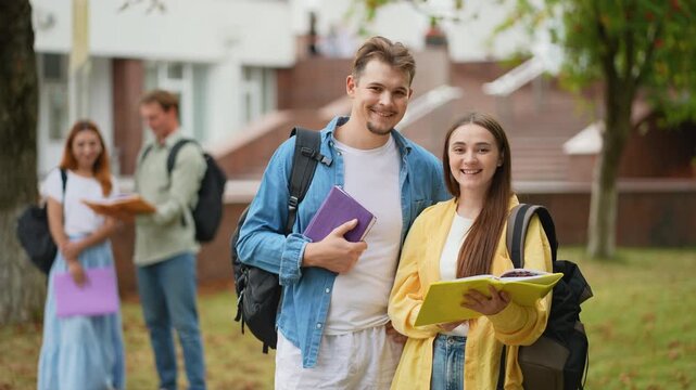 Happy college students smiling and holding books at campus