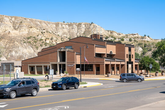 MEDORA, ND - 26 AUG 2026: Billings County Courthouse brick building with Badlands buttes behind and cars in street, Medora, North Dakota.