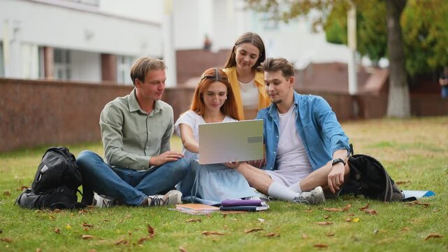 Group of university students studying together on campus lawn