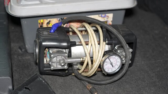 Close-up of vintage air compressor with coiled hoses and pressure gauge