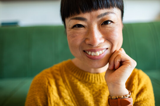 Smiling woman resting chin on hand at home