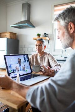 Couple having online doctor consultation at home kitchen