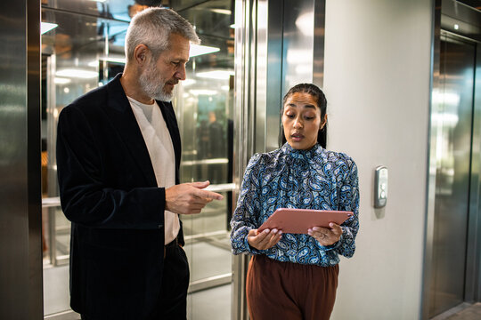 Colleagues reviewing a tablet near office elevator