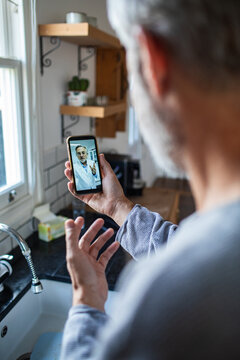Man having telehealth video call with doctor in kitchen