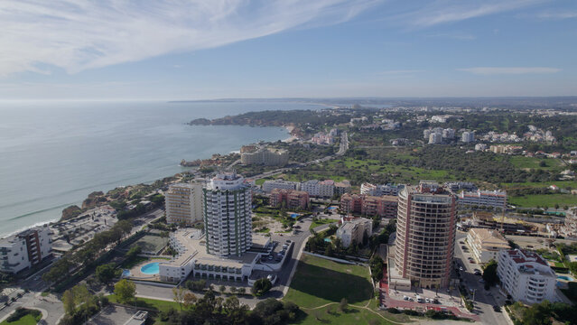 Aerial view of Praia da Rocha with high-rise hotels, coastal architecture, and green spaces along the Atlantic coastline in Faro District, Portugal.