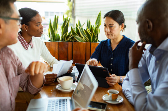 Woman pointing at tablet during team meeting in cafe