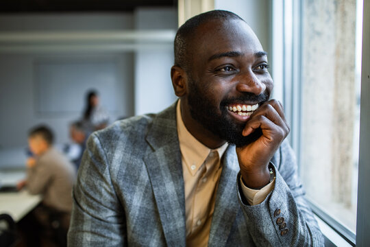 Smiling businessman looking out the window during office meeting