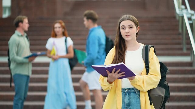 Young female student reading and smiling on campus stairs