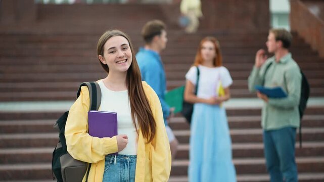 Young female student smiling with books at university campus
