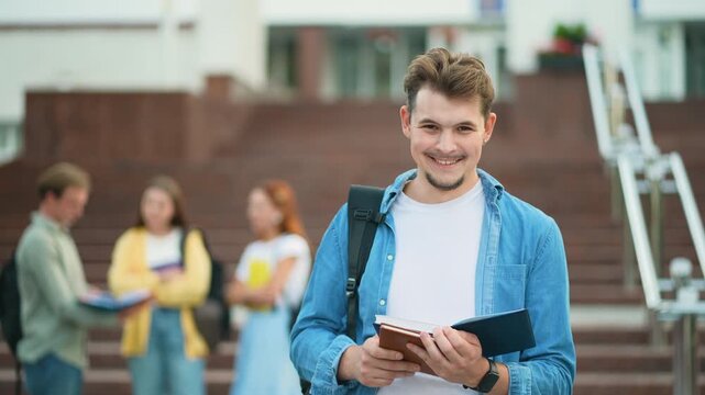Young male student smiling at camera outside university