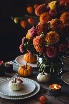Beautiful elegant autumn table setting for thanksgiving family dinner or wedding with dahlias. Orange pumpkin, floral centrepiece. Cozy fall home atmosphere. Wineglass, romantic marriage proposal