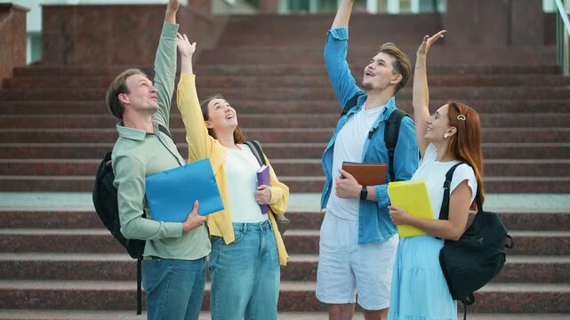 Group of university students celebrating together on campus stairs