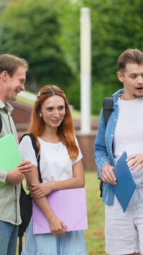 Group of happy college students talking outdoors on campus
