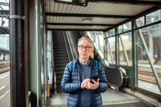 Senior man using smartphone at train station