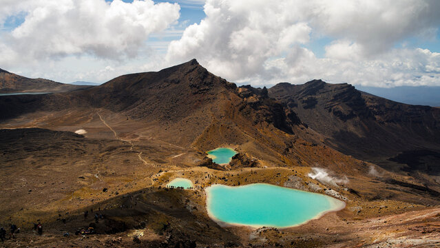 Aerial view of the Emerald Lakes at Tongariro Alpine Crossing with volcanic terrain, steam vents, and hikers on the trail in Manawatu-Whanganui, New Zealand.