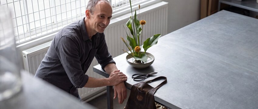 Florist betrachtet fertiges florales Gesteck im hellen Atelier