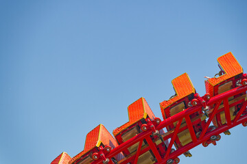 Bright red roller coaster seats against clear blue sky at amusement park © Holger