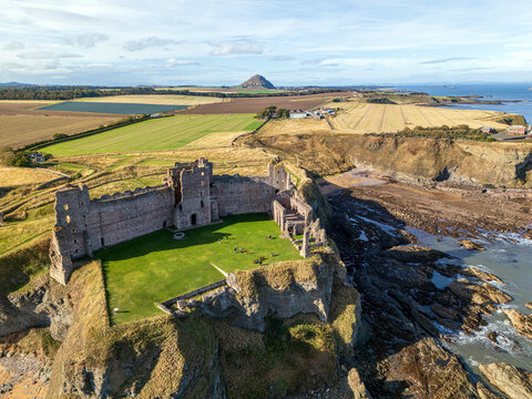 Aerial view of Tantallon Castle, a ruined medieval fortress on a cliff edge overlooking the North Sea, with green grass and surrounding fields in North Berwick, Scotland, United Kingdom.