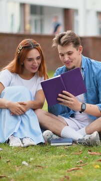 Young couple reading a book together sitting on the grass