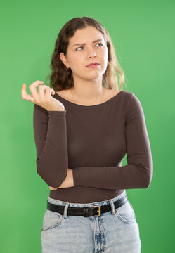 Female model acts forgetful on green backdrop, with worried expression during video scene