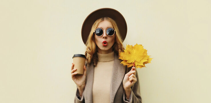Autumn portrait of beautiful surprised woman with yellow maple leaves, stylish emotional girl