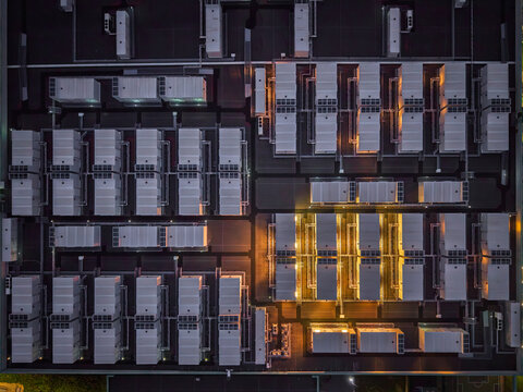 Aerial view of a data center rooftop featuring rows of industrial cooling units and HVAC equipment with some sections illuminated by warm lighting in The Netherlands.