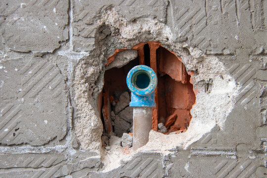 Blue PVC water pipe fitting exposed in wall opening. Focus on plumbing installation, piping, renovation, and construction.
